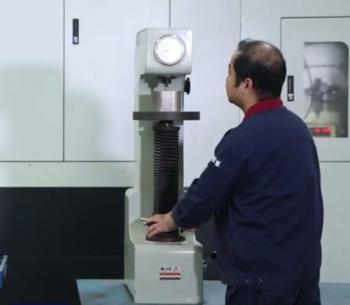 Technician measuring screw hardness on a testing machine